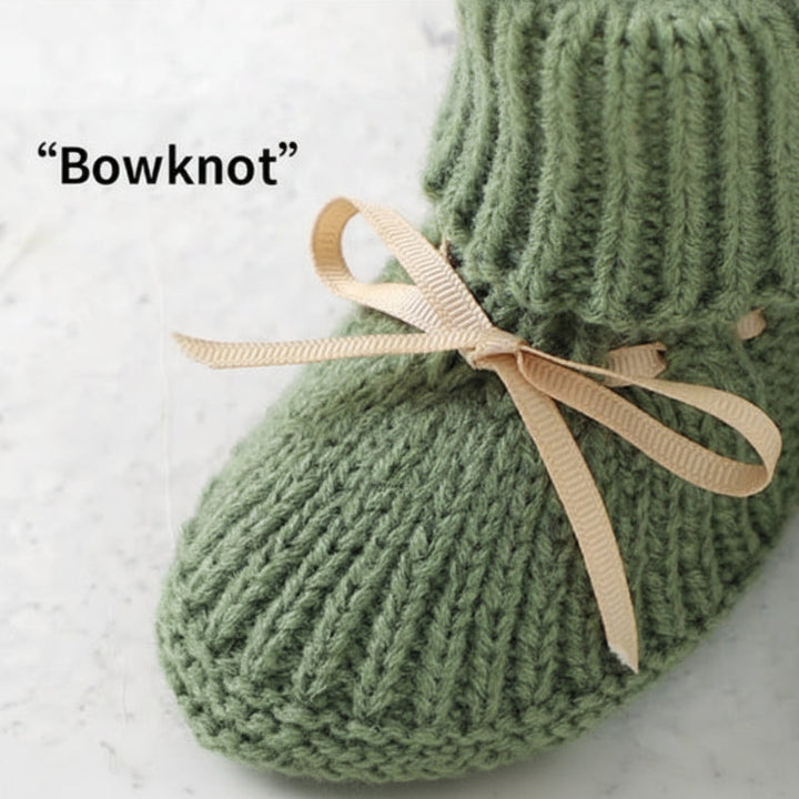 Beige ribbon bow detail on a green knitted baby bootie