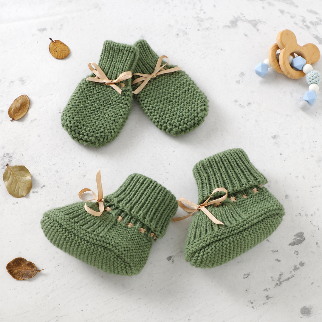 Green knitted baby booties and matching mittens with beige ribbon bows