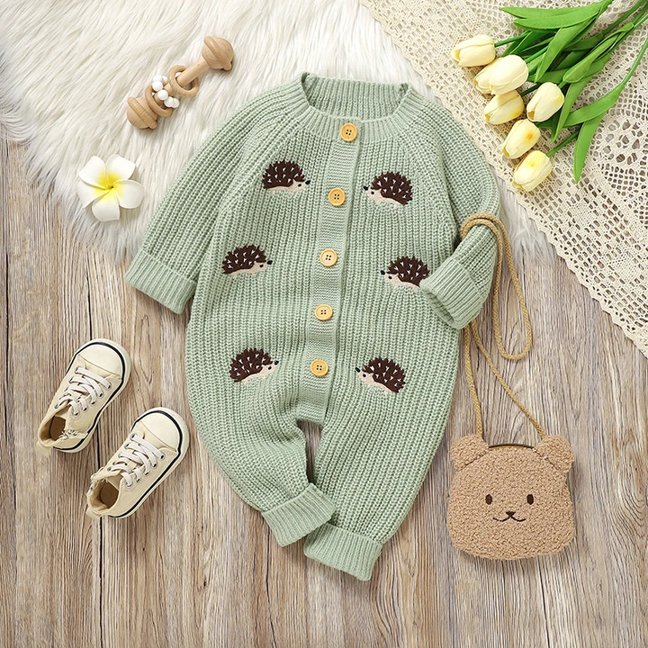 Green hedgehog baby jumpsuit styled beside yellow tulips and a small bear-face bag.