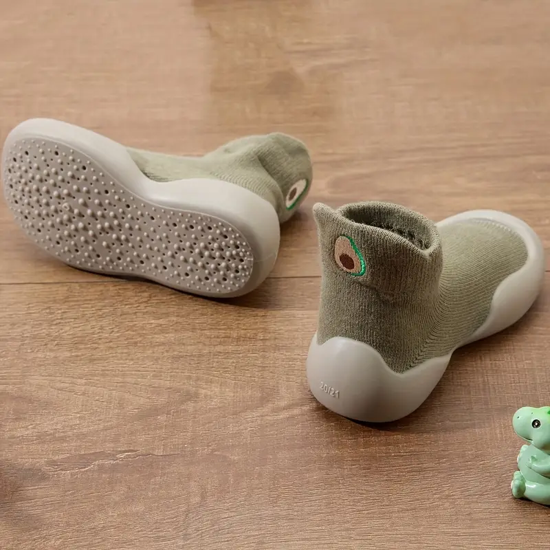 Green baby shoes showing the textured outsole, sock-style upper, and avocado detail