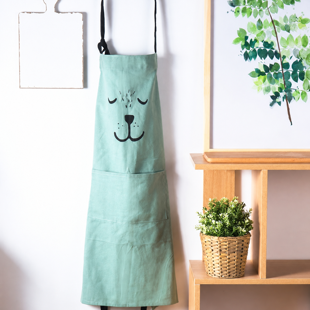 Green bear apron hanging beside a window with its front pocket visible
