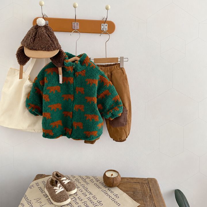 Green bear-print fleece jacket hanging beside a brown hat and shorts