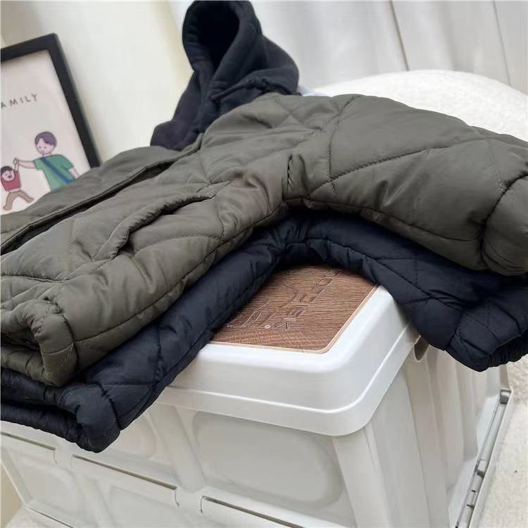 Army green and navy blue padded jackets stacked on a chair.