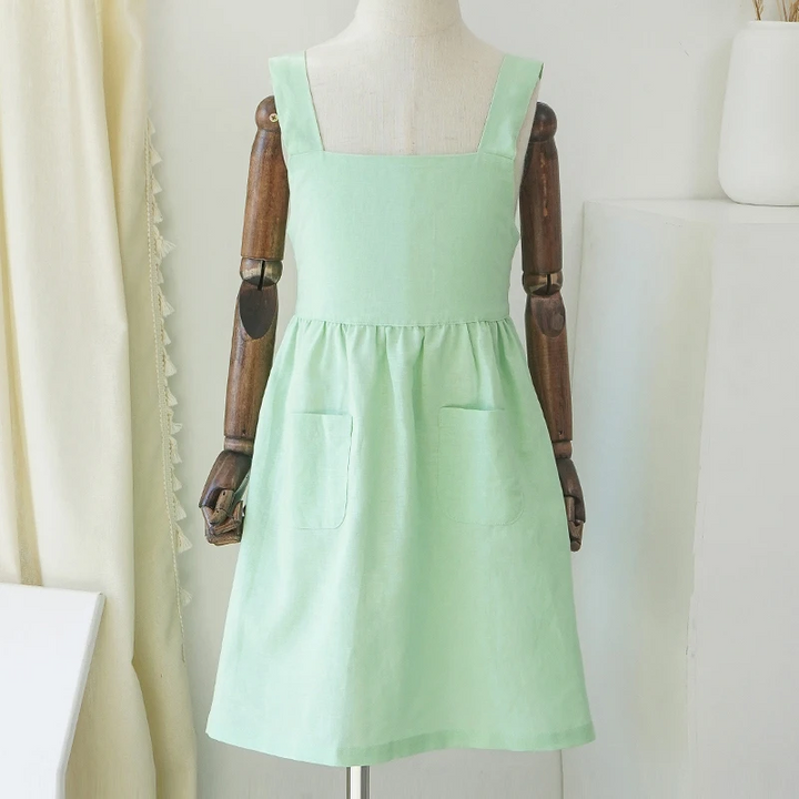 Front view of the green cotton dress on a mannequin, showing wide straps and two patch pockets