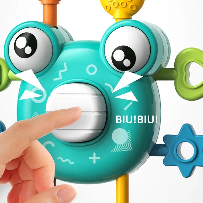 Finger pressing the white center button on a green crab sensory toy