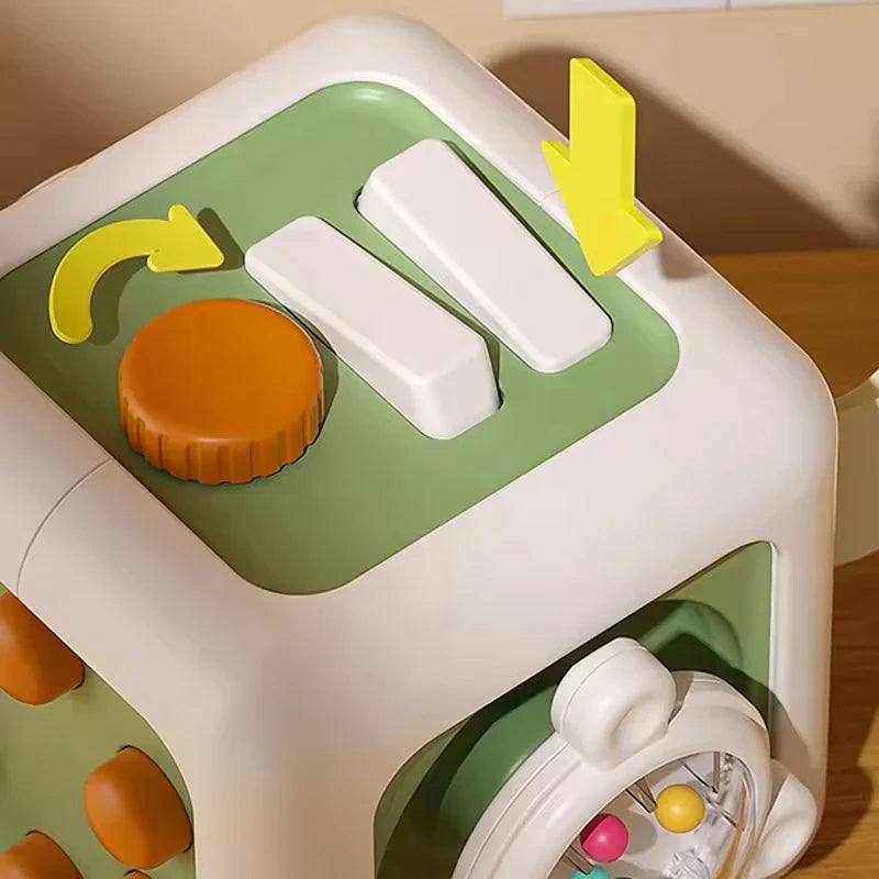 Orange turning knob and two white press bars on a green activity cube