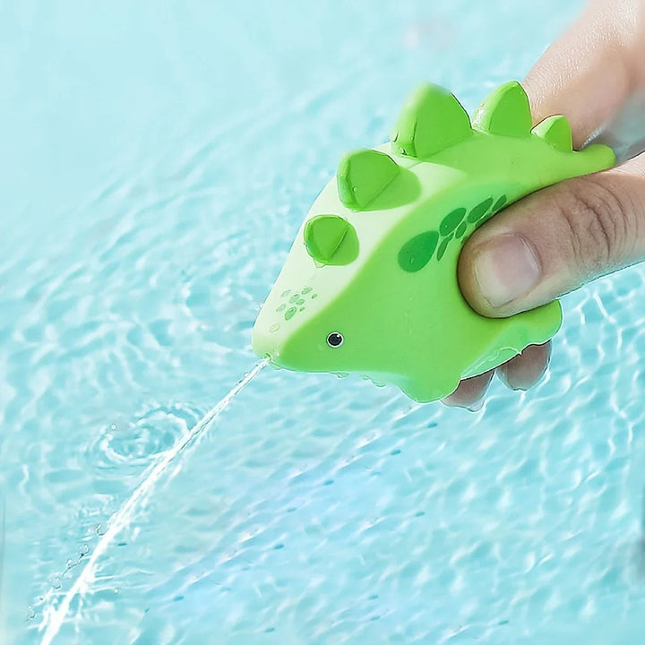 Hand squeezing a green dinosaur bath toy to spray water