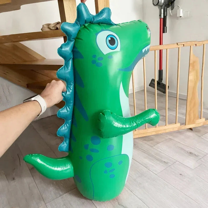 Green inflatable dinosaur punching bag held upright beside an indoor stairway