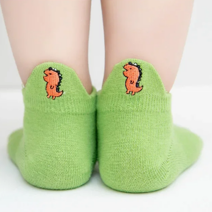 Back view of green low-cut socks with orange dinosaur motifs on the heel tabs