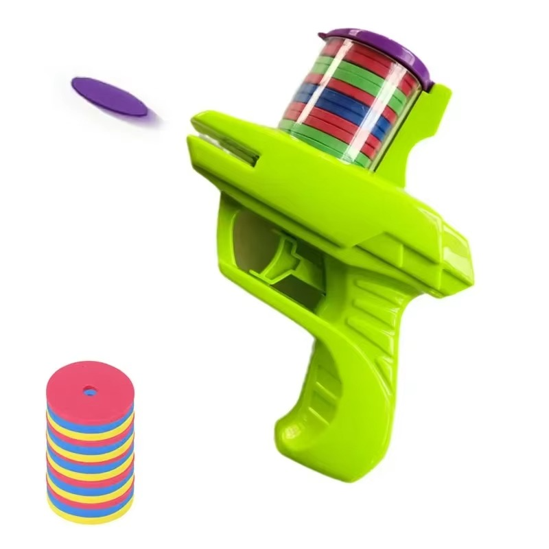 Green toy disc blaster with a loaded top cartridge, a purple disc, and a stack of multicolored discs.