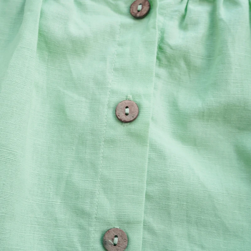 Decorative round buttons along the back of the green cotton dress