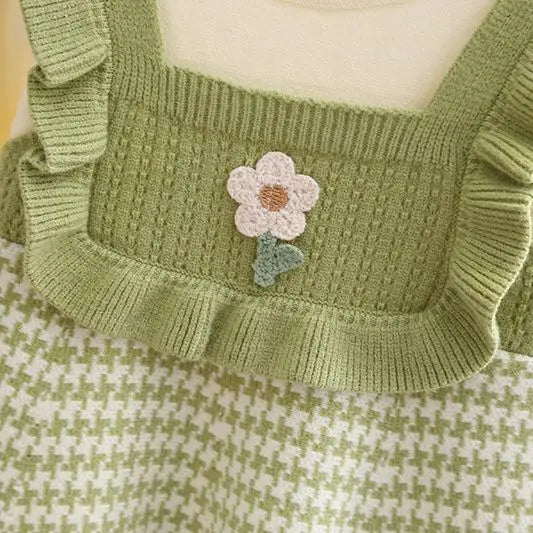 Close-up of the green dress showing its flower detail, knit texture, and ruffled edging