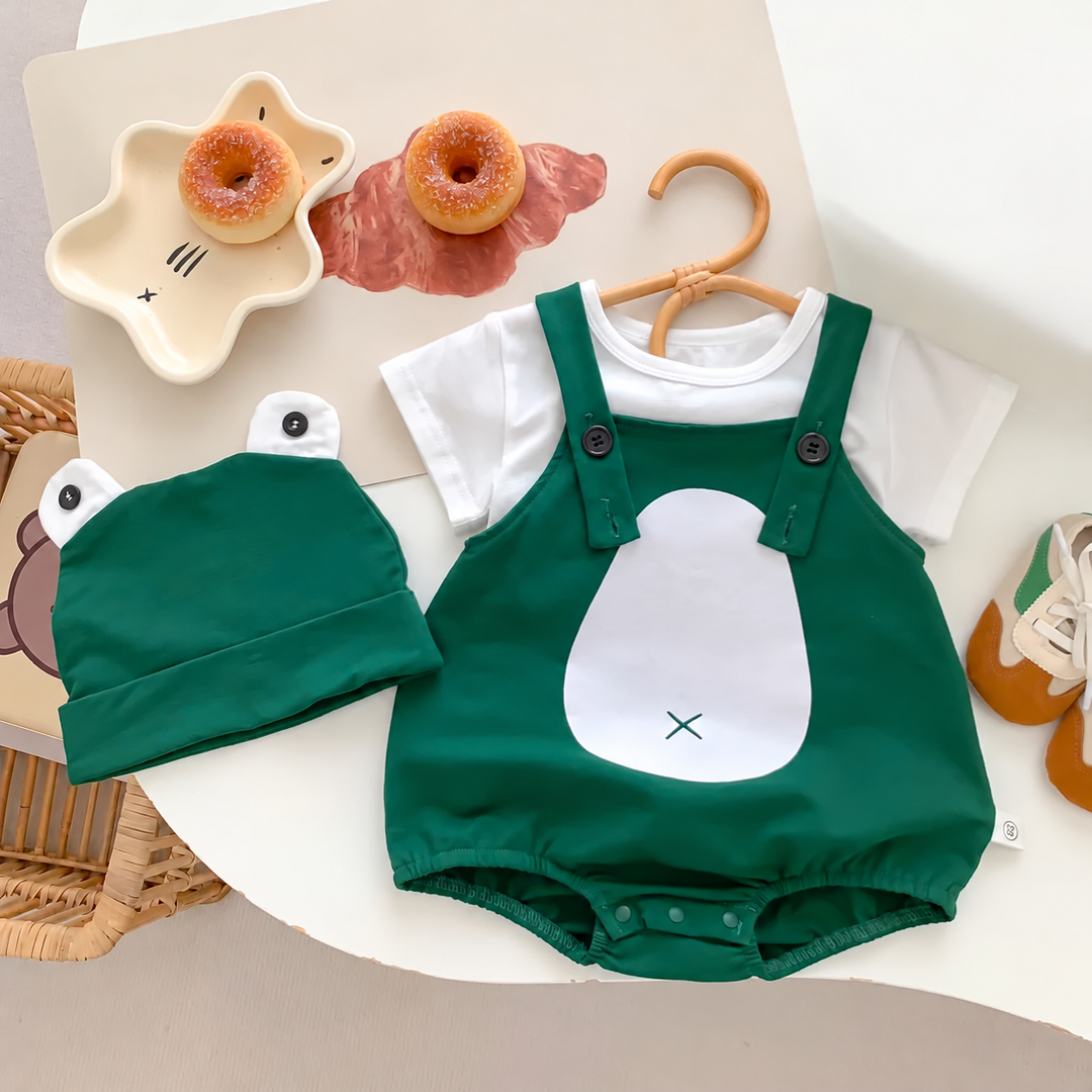 Green frog baby romper styled over a white top beside a matching frog-eye cap