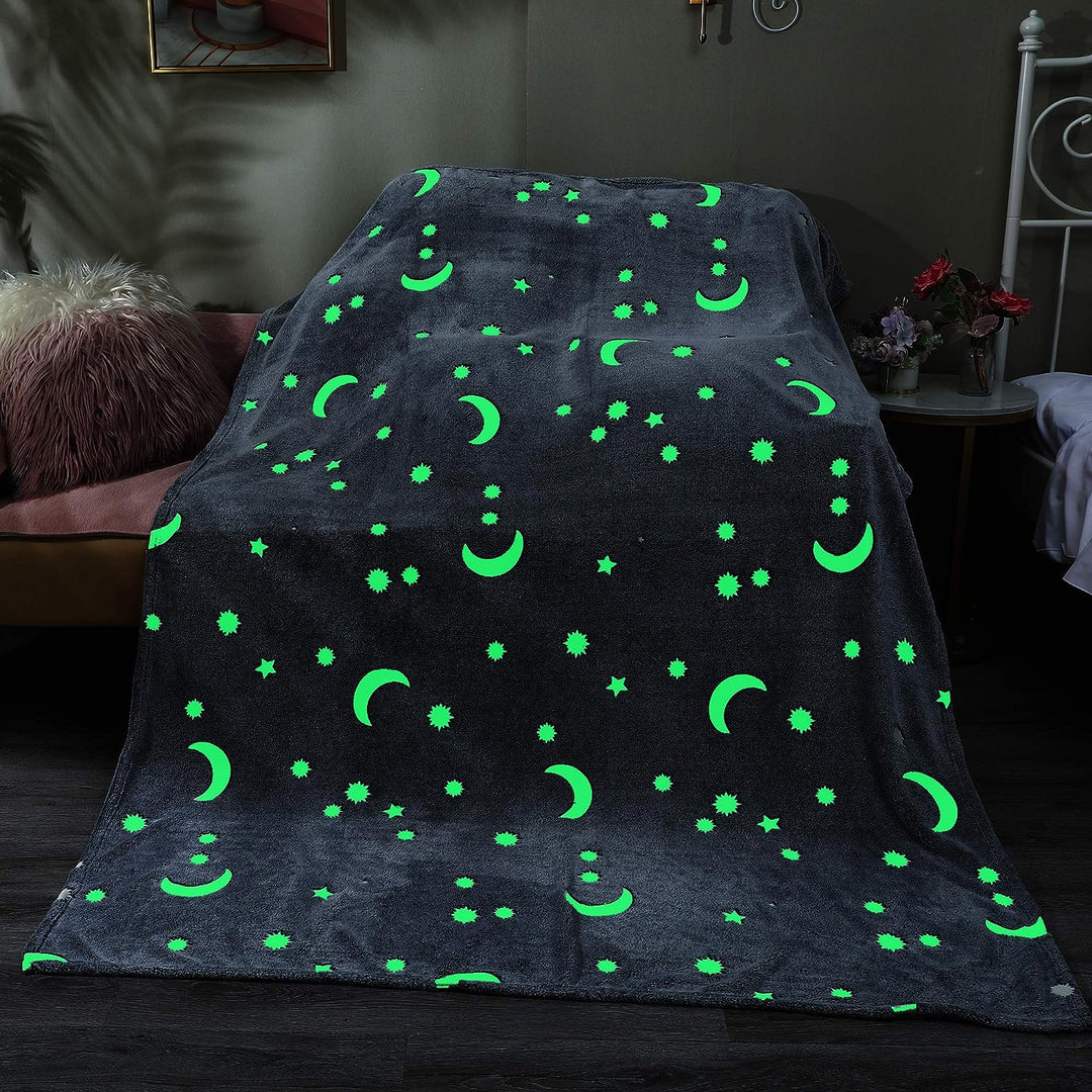 Sun, moon, and star motifs glowing green on a blanket in a dark room