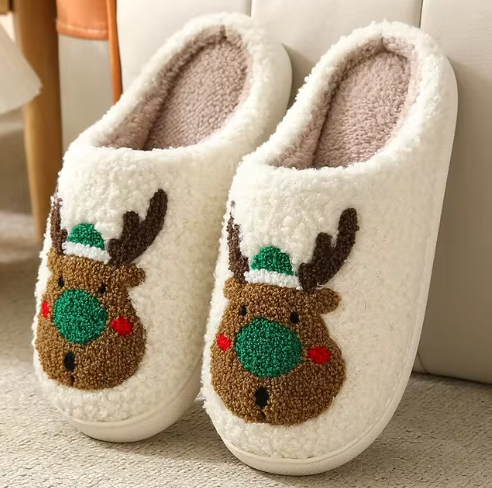 Cream slippers with green-nosed reindeer wearing green hats.