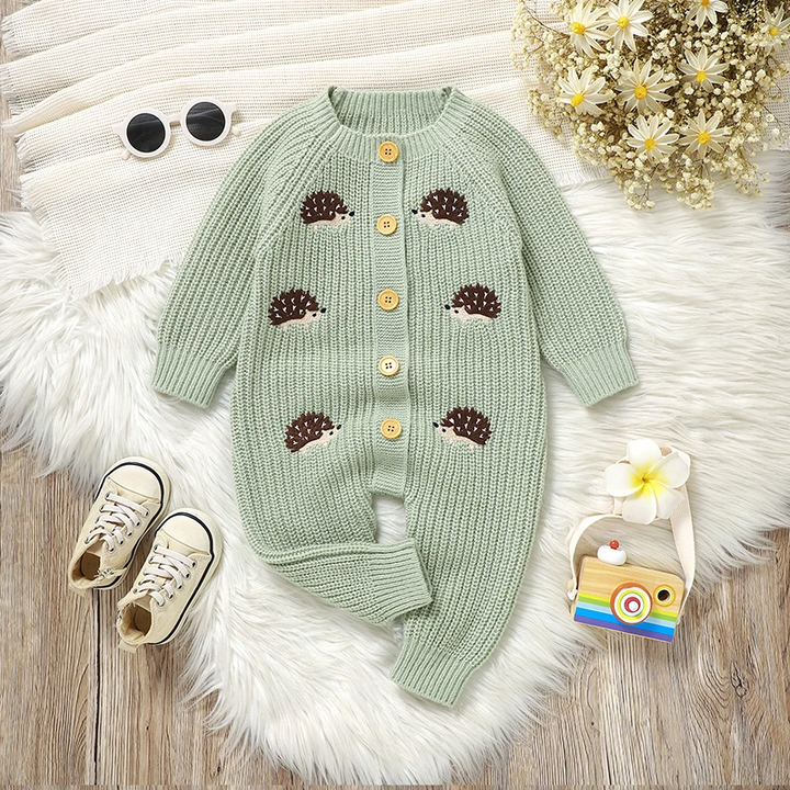 Green hedgehog jumpsuit with a button front and one leg folded on a white rug.