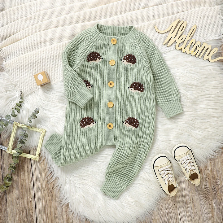 Green knit hedgehog baby jumpsuit with one sleeve folded across the front.