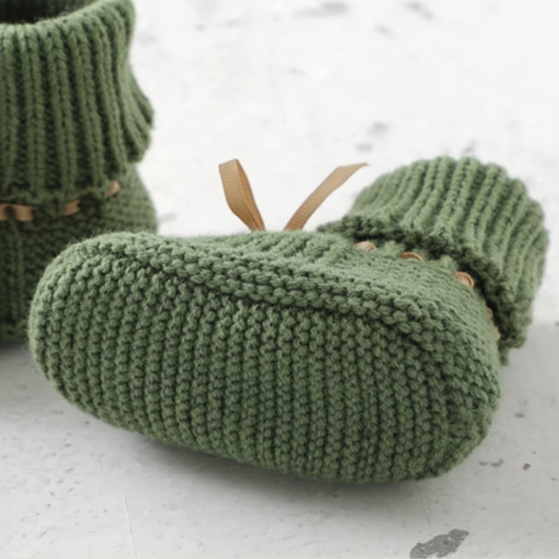 Green knitted baby bootie showing its textured sole