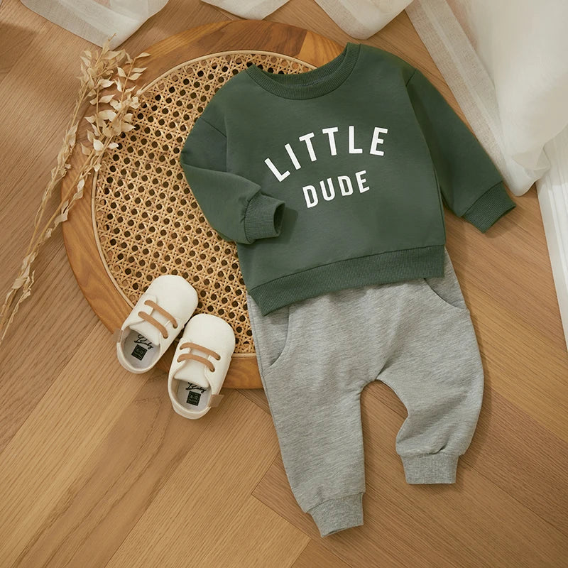 Green letter-print sweatshirt paired with gray cuffed pants in a flat lay