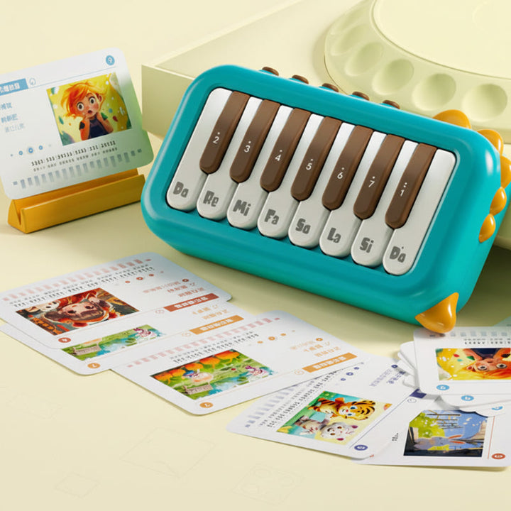 Green mini electronic piano with labeled keys beside illustrated music cards.