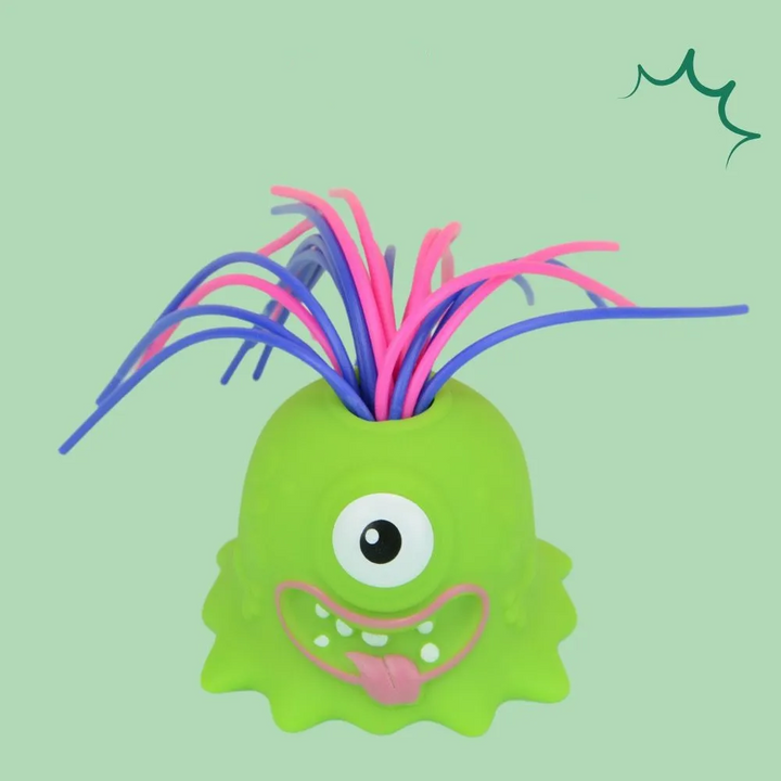 Green one-eyed monster stress toy with pink and purple hair and a tongue-out smile