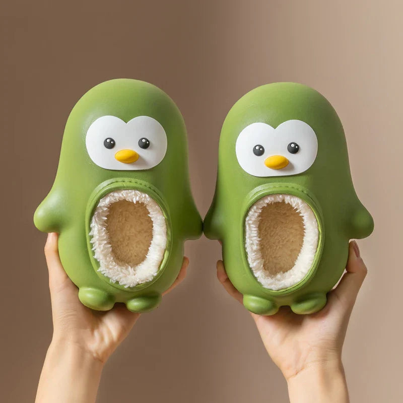 Pair of green penguin slippers held upright with soft-lined openings visible