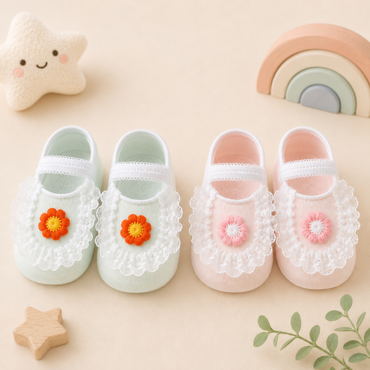 Green and pink baby socks with white lace trim and colorful flower accents