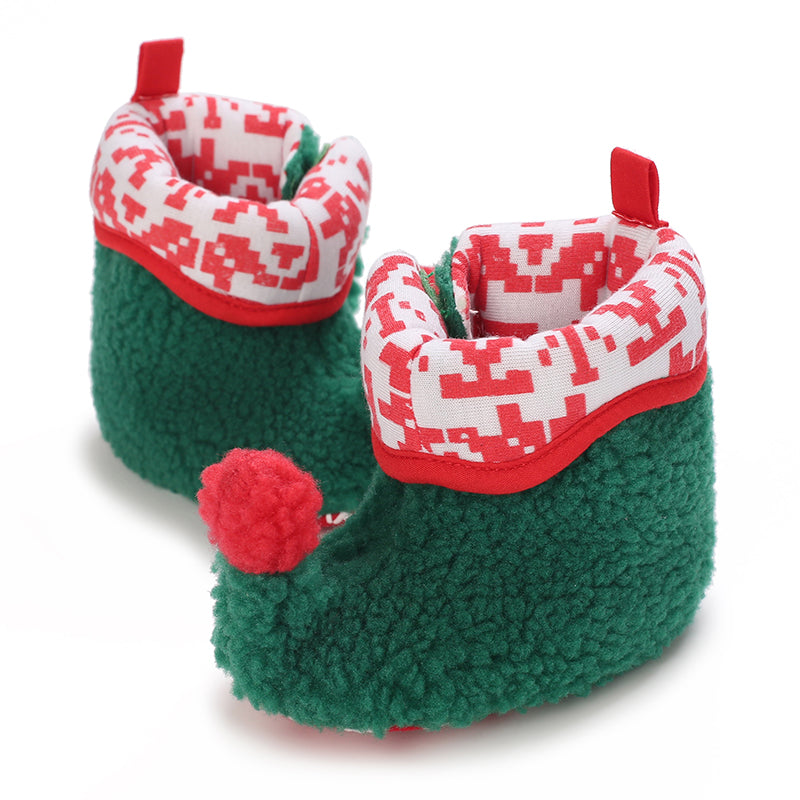 Green plush baby booties with red-and-white patterned cuffs and a red pom-pom