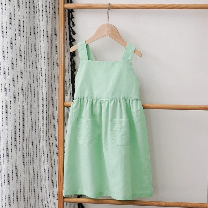 Green sleeveless dress hanging from a wooden rack, showing the front pockets