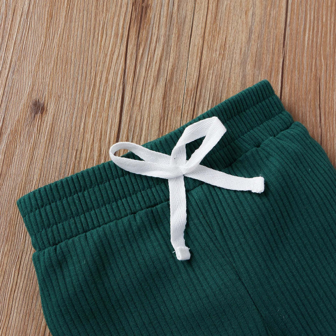 Close-up of green ribbed baby pants with a gathered waistband and white tie