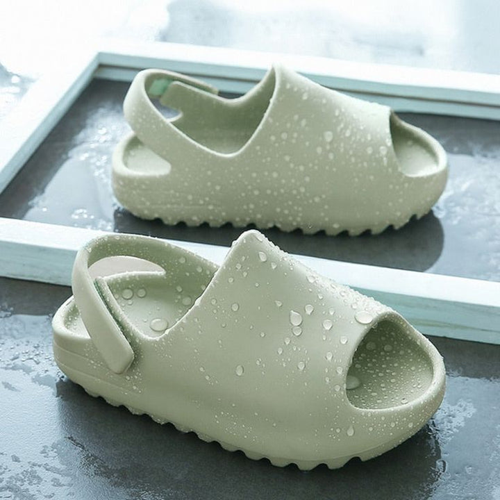 Green sandals covered with water droplets, showing their open toes and heel straps.