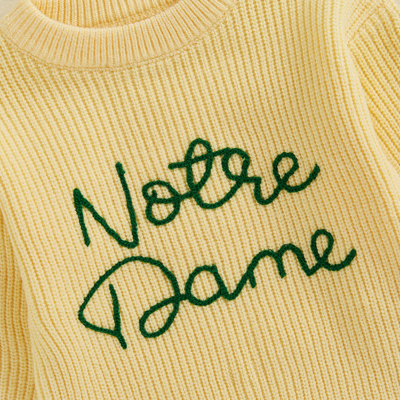 Green script embroidery across the front of the yellow knit sweater.