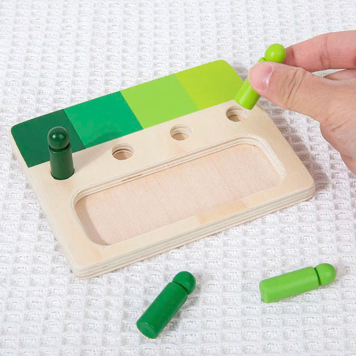 Hand positioning a light green peg above a hole in a wooden shade-matching board