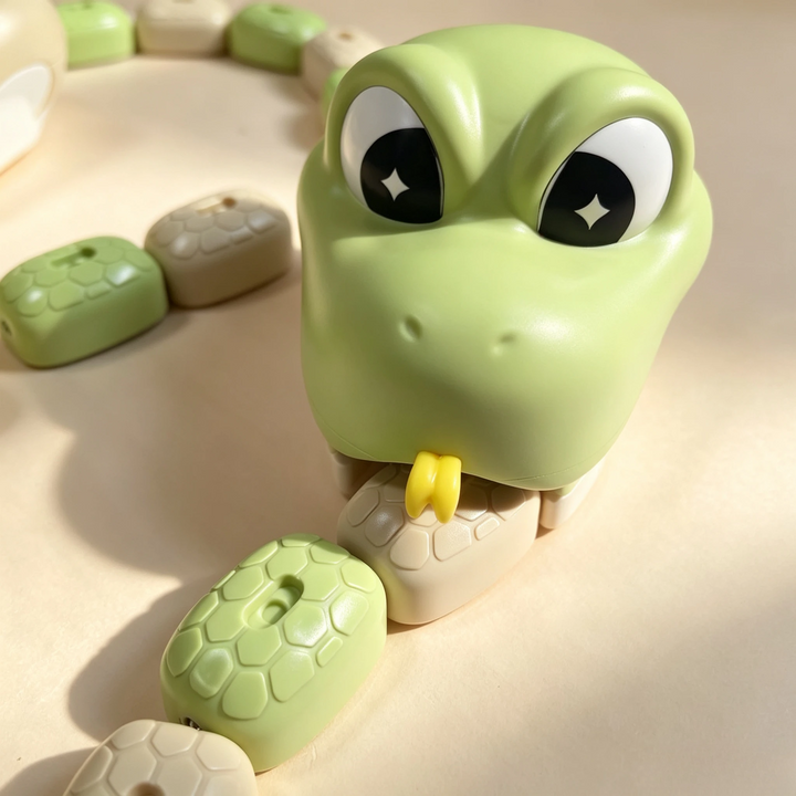 Green snake toy head with large eyes, a yellow tongue, and linked body segments