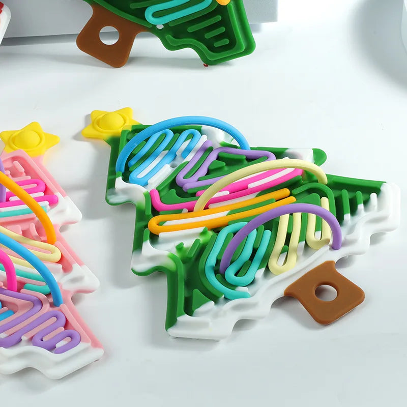 Close-up of colorful cords looped over the channels of a green snow-accented tree fidget
