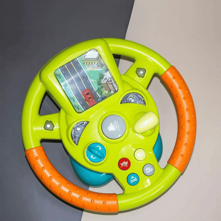 Green steering wheel toy with orange grips, a road scene, colored buttons, and a yellow lever