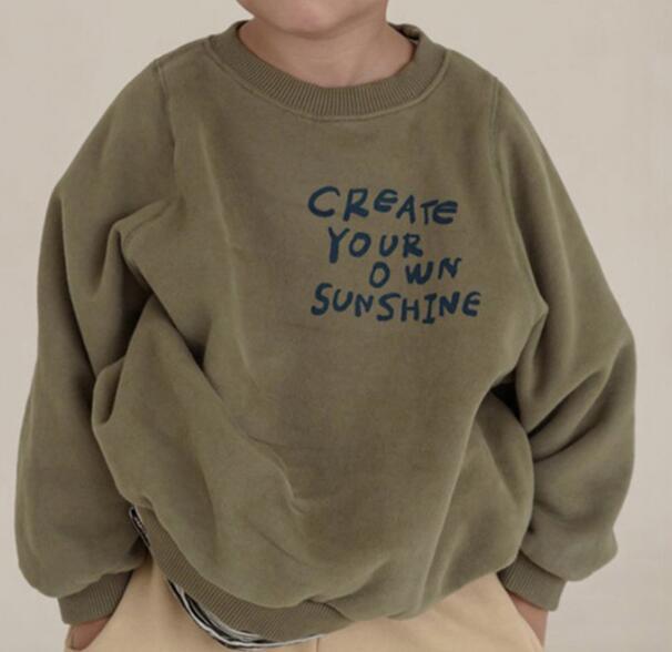 Child wearing a green sweatshirt with Create Your Own Sunshine lettering