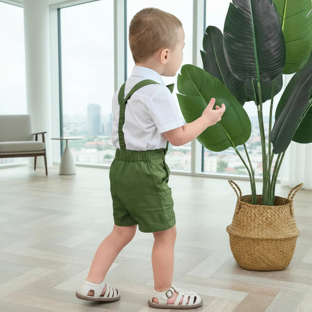 Rear view of a boy wearing green suspender shorts with a white short-sleeve shirt