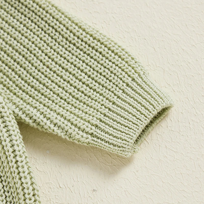 Close-up of a green knit sweater sleeve with a ribbed cuff.