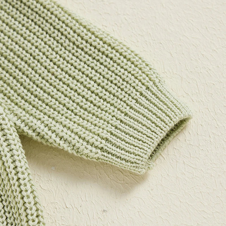 Close-up of a green knit sweater sleeve with a ribbed cuff.