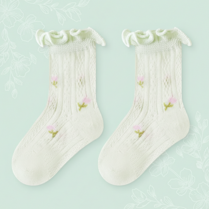Pair of pale green baby socks with floral details and ruffled cuffs.