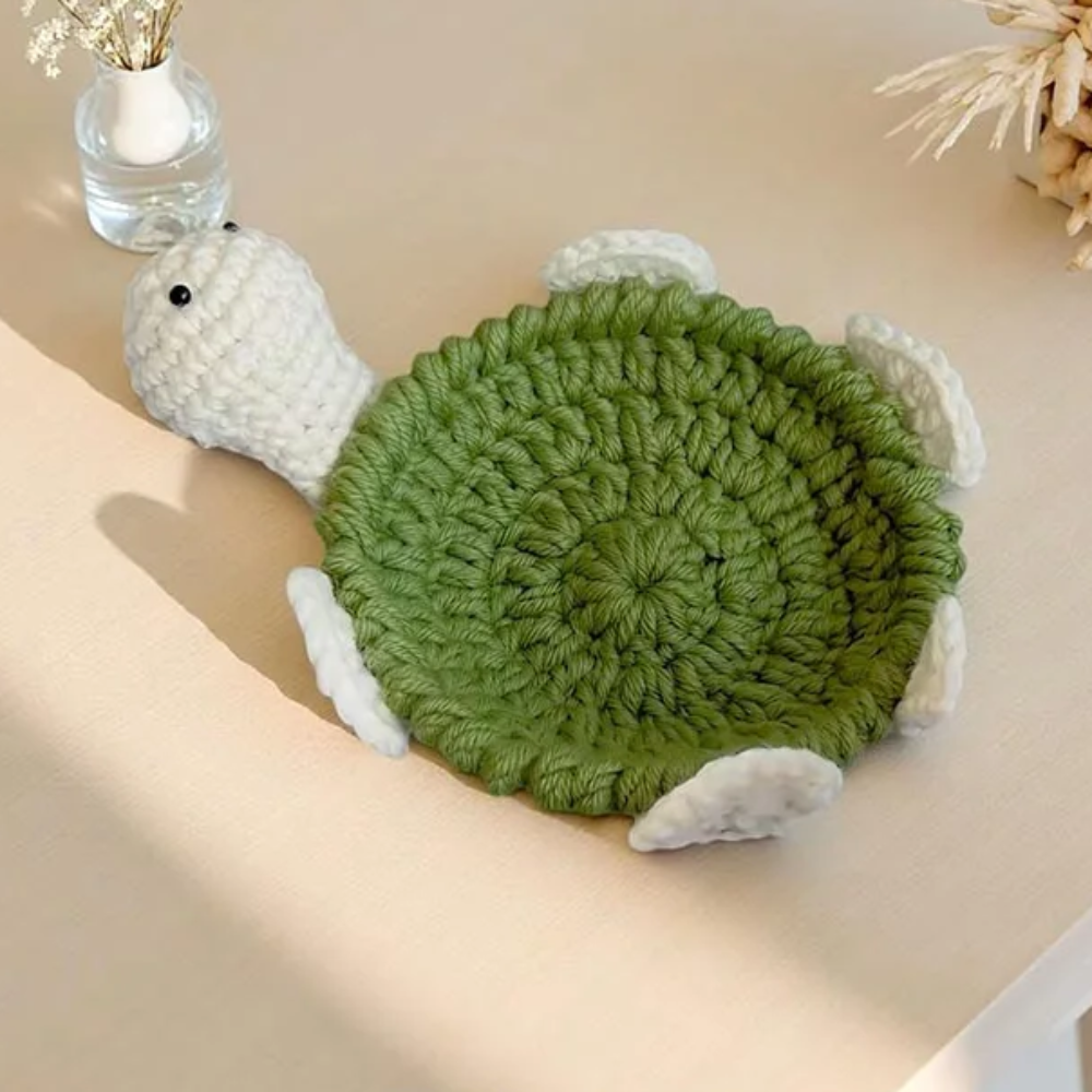 Green turtle coaster with an olive crocheted center and white head and feet