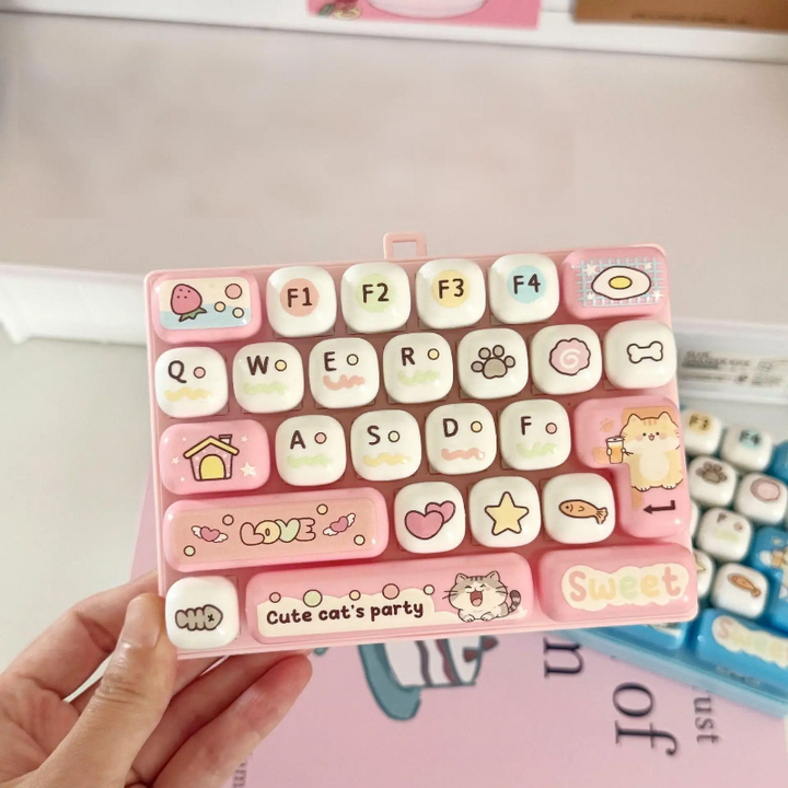 Hand holding a light pink fidget keyboard with letter keys and cat illustrations