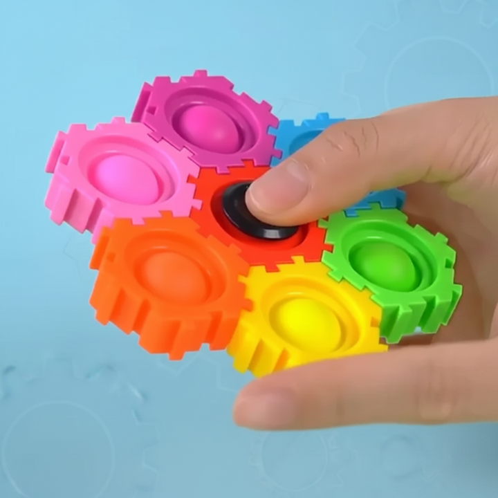 Hand holding a cluster of colorful gears with a thumb on the black center.