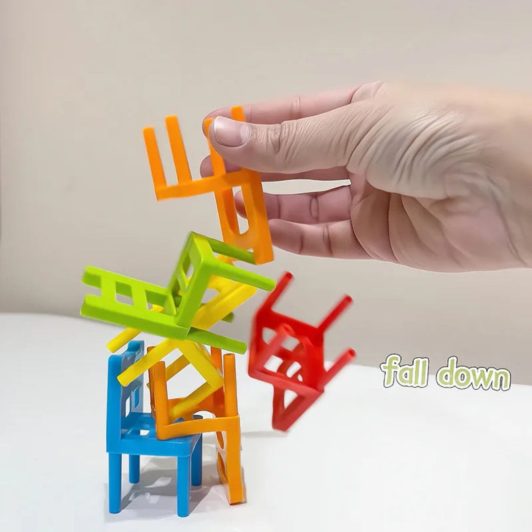 A hand holds an orange chair above a small tower of colorful chairs