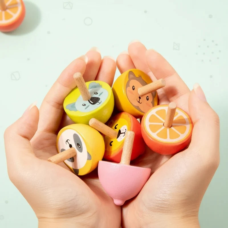 Hands holding colorful animal and fruit wooden spinning tops