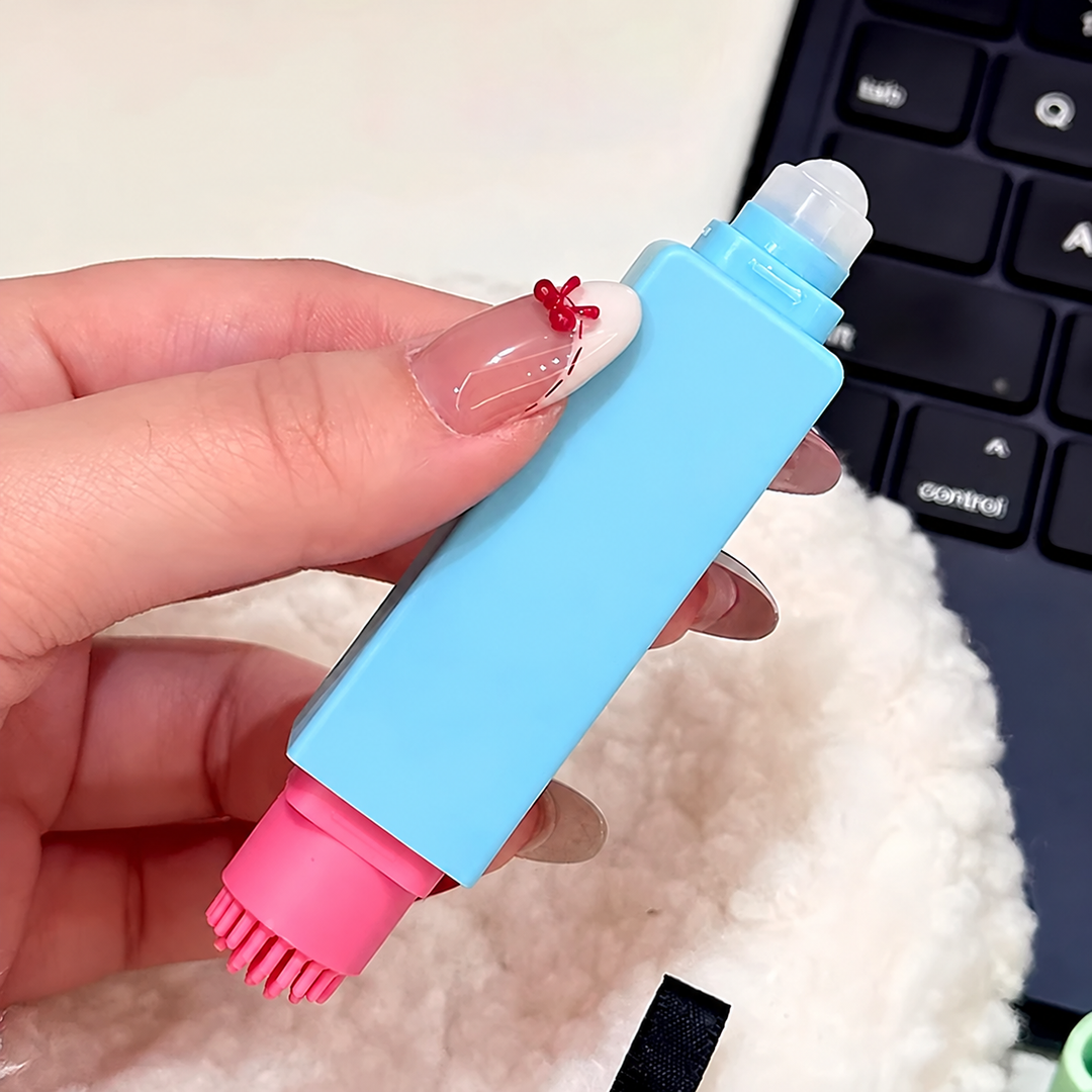 Blue stain remover pen held with the liquid applicator and pink brush uncovered