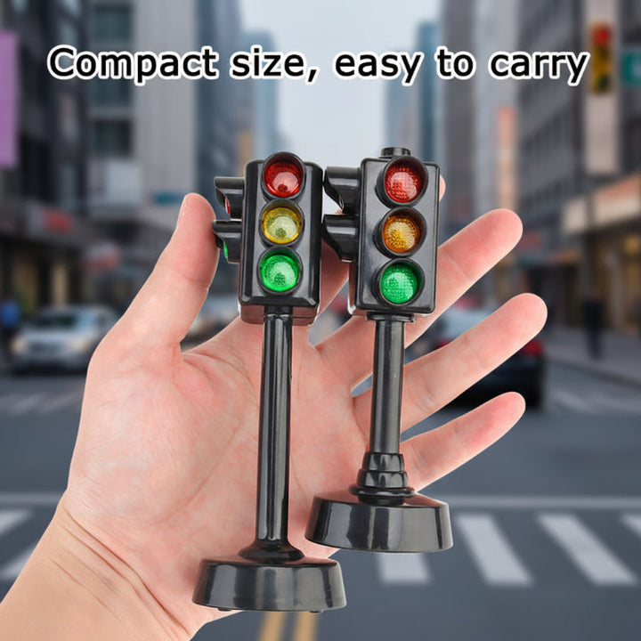 Two compact black traffic-light models resting in an open hand.