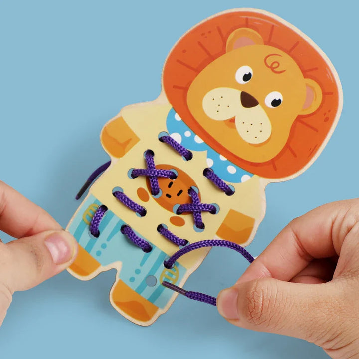 Hands threading a purple cord through a lion-shaped wooden lacing board