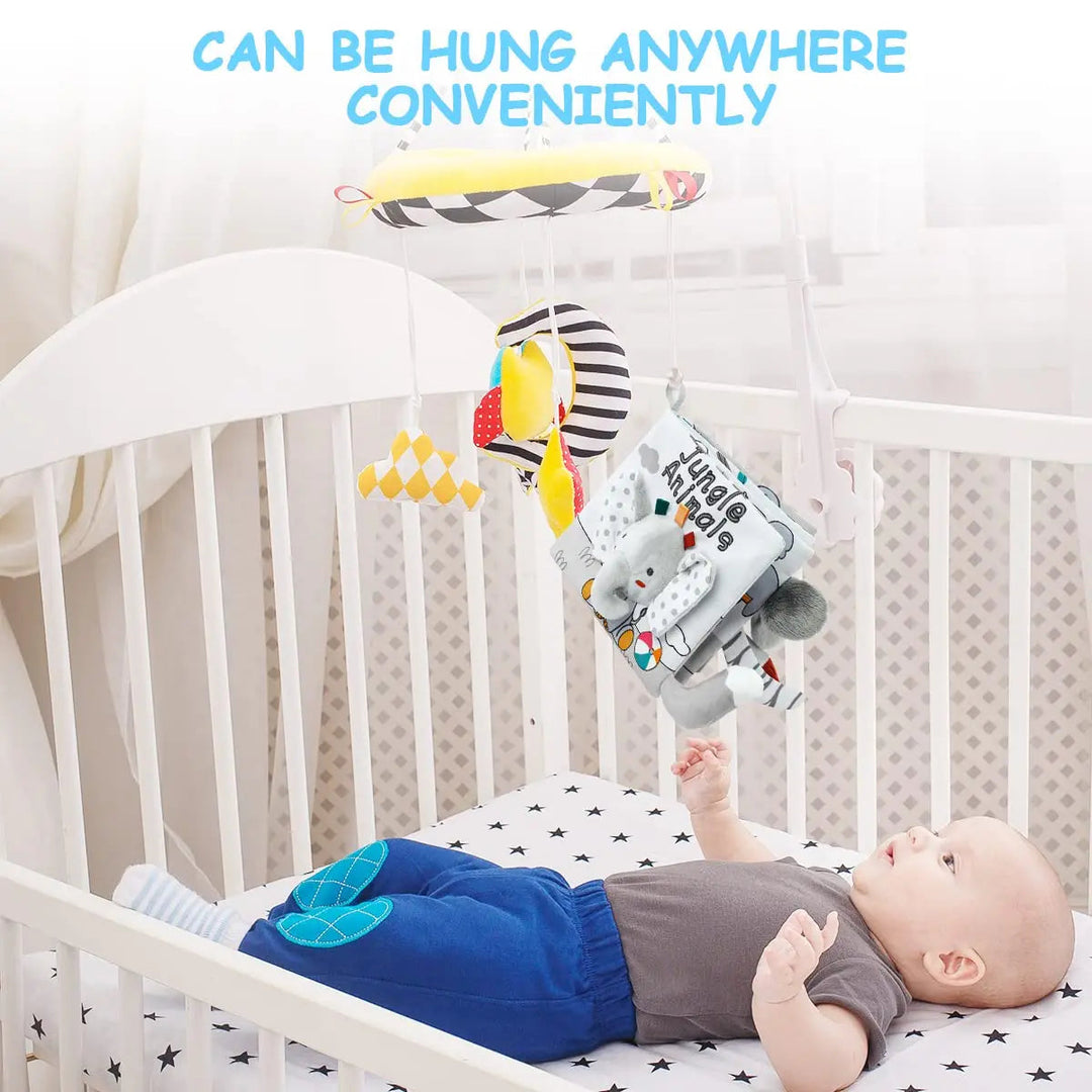 Animal sensory book hanging above a crib while a baby reaches toward its fabric details